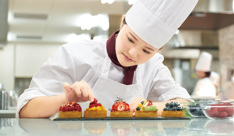 ケーキの飾り付けを行う学生