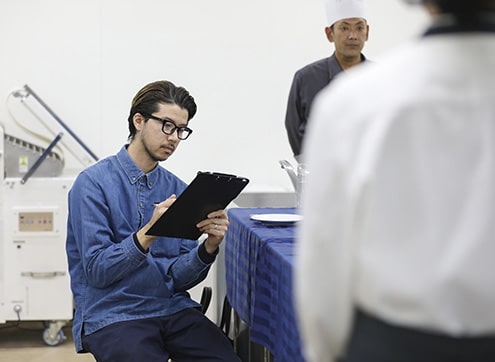 プレゼンを聞きメモをとる講師