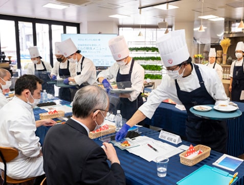 審査員の前に料理を置く学生たち