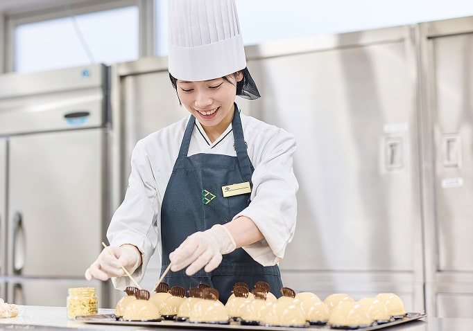 ケーキの飾り付けを行う学生